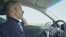 Male driver sitting in an autonomous car, watching as the car drives by itself