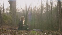 Smiling young woman reading her bible, writing notes, and admiring nature
