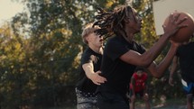 Young men playing basketball on an outdoor court on a sunny day