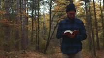 a man reading a Bible in the woods in fall 