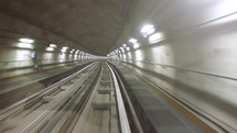 Perspective view of subway tunnel and tracks seen from moving train, with shimmering neon lights
