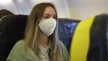 Woman in medical mask inside the airplane.