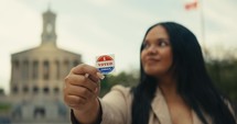 Young woman smiling with an ‘I Voted’ stickers and pin 