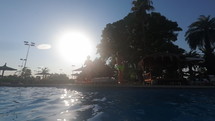 Kids jumping into pool in slo mo with sun behind them