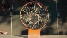 Young men playing basketball on an outdoor court on a sunny day