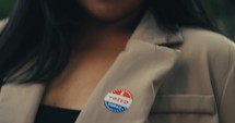 Young woman smiling with an ‘I Voted’ stickers and pin 