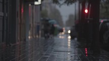 A blurred view of a paved street on a rainy evening