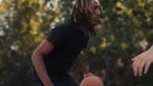 Young men playing basketball on an outdoor court on a sunny day