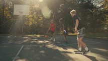 Young men playing basketball on an outdoor court on a sunny day