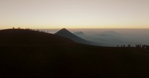 People On The Mountain Peak Of Acatenango Volcano Overlooking Agua Volcano At Dawn In Guatemala. Aerial Drone Shot