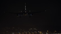 Commercial airplane landing at an airport at night.