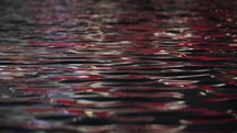 Rippling water surface with red light reflection