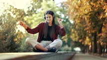 Portrait of attractive girl dancing with headphones in park