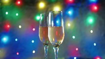 glasses of champagne under colorful lights background 