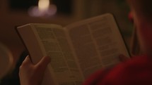 Child reading bible by the Christmas tree and Fireplace