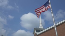 church steeple and American flag on a flag pole 