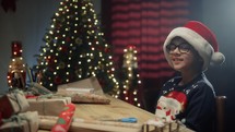 Kid preparing Christmas gifts for his family on table