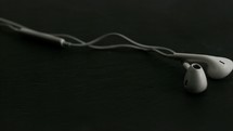 white earbuds falling on black background.