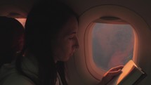 Woman reading book inside airplane. Happy traveler reading a book in an airplane.