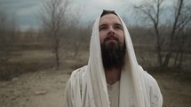 Jesus Christ, bible prophet or religious Christian man in white tunic with a beard in meditation, prayer and worship in nature.