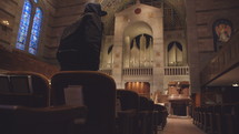 hooded man sits in an empty church 