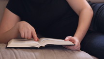 a girl reading a Bible on a couch 