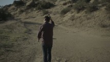 man walking down a dirt road 