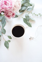 A cup of coffee and a bouquet of flowers on a white surface.