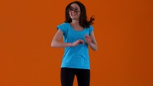 Woman dancing and jumping in front of an orange background.