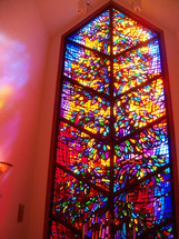 A large stained glass window called The Window to Heaven fills a chapel with warmth and glowing light as church members come in to pray and have quiet time before the Lord. 
