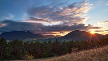Epic sunset with colorful clouds in beautiful mountain hilly landscape, timelapse