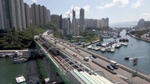 Train and cars on the bridge in Hong Kong. Aerial drone view. Harbour view with boats and yachts. 