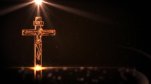 Jesus Christ on cross with golden light on black background with defocused lights spinning around. Easter background. Seamless looping 4k