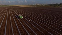 Aerial footage of farm workers working in a field with tractors