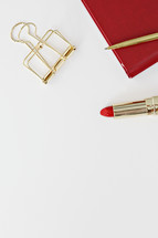 gold clip, red planner, red lipstick, and gold pen 