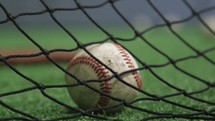 baseballs on a field by netting 
