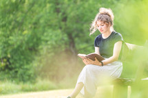 Young woman reading Bible on bench