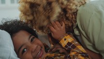 African American Mother Rubbing Noses with Joyous Little Son Lying on Sofa
