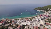 Drone view of the beautiful quiet beach town of Himare, Albania with a stunning view of the Ionian Sea. Hillside full of greenery and beautiful view of the city.