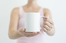 a woman holding out a coffee mug 