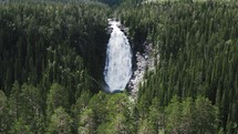 aerial view over a waterfall and green forest 