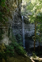 Waterfall over stone mountain with trees and plants