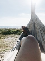 a woman sitting in a hammock on a beach 