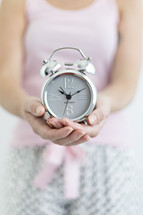 a woman holding an alarm clock 