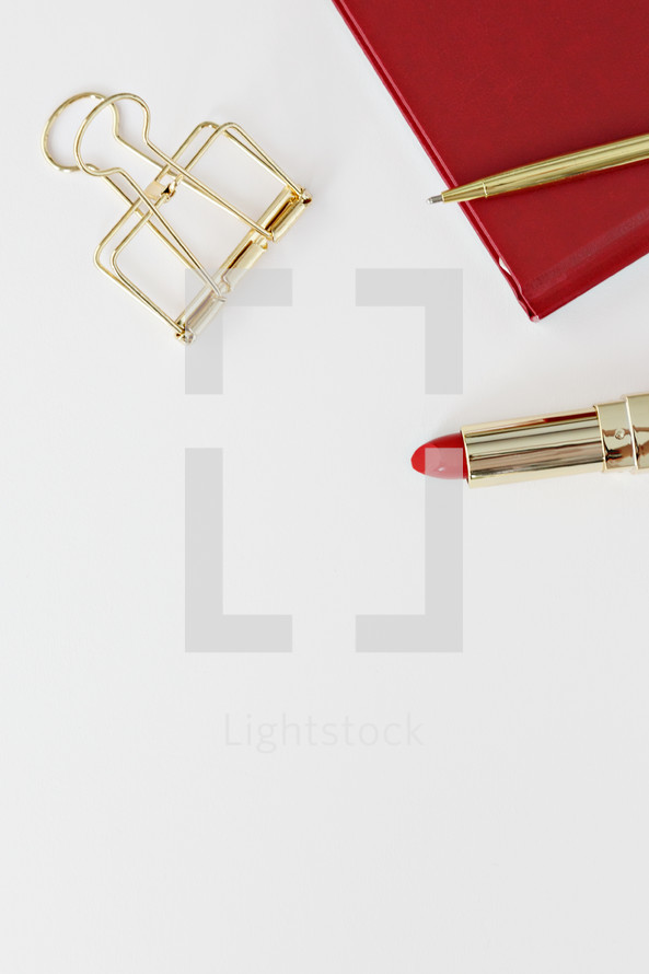 gold clip, red planner, red lipstick, and gold pen 
