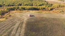 Aerial shot of a moving combine harvester collecting sunflower seeds in autumn. Agriculture food production. Combine harvesting, collects ripe sunflower grains. Harvest, Drone, Eco.