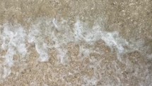 tide washing onto sand on a beach 