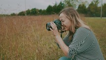 a woman taking a picture in a field 