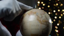 Santa calculating his road on a World map globe 