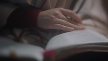 a woman turning the pages of a Bible 